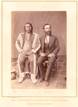 Sitting studio portrait of Native American (Tabeguache band, Southern Ute) Chief Ouray, and Otto Mears, an interpreter and businessman. Ouray wears beaded moccasins, leggings, shirt, and fringed coat, Mears wears a three piece suit.