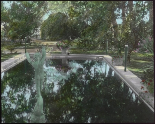 View of the yard at the George W. Gano house in Englewood (Arapahoe County), Colorado; landscaping includes a formal pond, urns of petunias, dracenas, and a nude nymph sculpture.