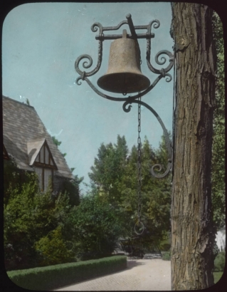 View at the George W. Gano house in Englewood (Arapahoe County), Colorado; shows a cast iron bell with an ornate wrought iron holder. The house has half-timbering in the gable.