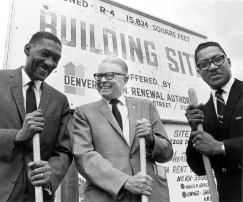 African Americans Omar Blair, representing the Denver Urban Renewal Authority and the Rev. Cecil W. Howard, of the Shorter Community AME Church, along with Denver Mayor William H. McNichols hold shovels at the ground breaking for the Denver Urban Renewal Authority Whittier project in the Whittier neighborhood of Denver, Colorado. A sign reads, "(?) R-4 15,824 Square feet, Building Sit[e] [o]ffered by Denver [Urba]n Renewal Author[ity]."