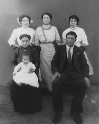 Studio group portrait taken at the time of the baptism of Mercedes Gómez in Vigil (Las Animas County), Colorado. Members of the Hispanic American Gómez family are identified: top left to right: Carolina Gómez, Lucía Gómez, Domecinda Gómez. Front, left-right: Juanita M. Girardot Gómez, Mercedes Gómez (baby). and Leandro Gómez.