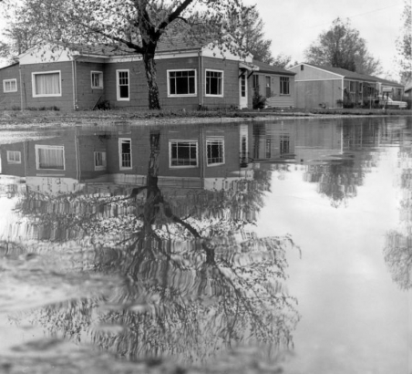 View of South Platte River flood damage in Denver, Colorado; shows houses reflected in water.