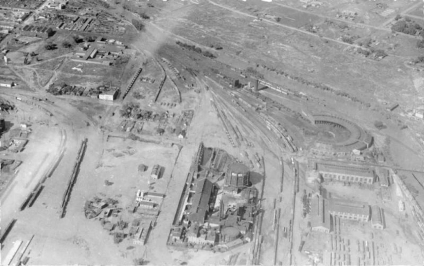 Aerial view of Cherry Creek flood damage in Denver, Colorado after the Castlewood Canyon Dam break; shows railroad yards, the Denver Gas Works, a roundhouse, and the South Platte River.