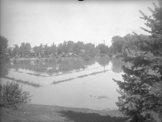 View of Cherry Creek floodwater in Denver, Colorado after the Castlewood Canyon Dam break; shows the Sunken Gardens under water.