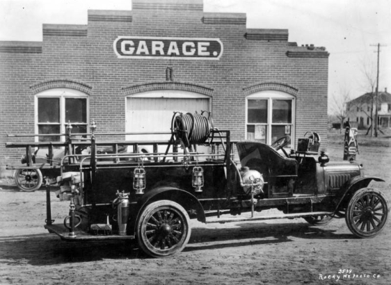 View of a hook and ladder truck in Denver, Colorado. A sign on a brick building reads: "Garage."