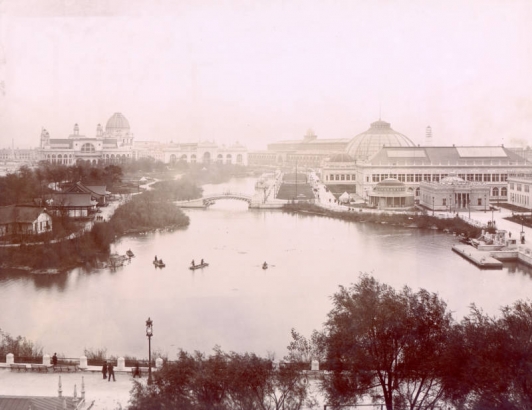 Overview of several exhibition building at the World's Fair (World's Columbian Exposition) in Chicago, Illinois. Building include the Transportation Building, Mines and Mining Building, Electricity Building, and Administration Building.  Wooded islands and row boats dot the Lagoon. Print 102.