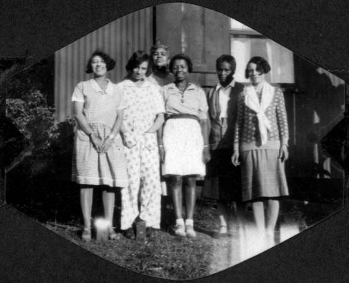 African American women, staff members and visitors pose together (includes "Mother" Gross the camp cook, and Mary Wood aka "Woody") at Camp Nizhoni in Lincoln Hills (Gilpin County) Colorado. They wear dresses, pants, shorts, blouses; one wears a scarf.