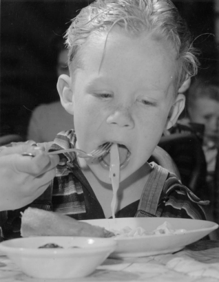 A boy eats noodles probably part of a hot lunch program at an unidentified school in Denver, Colorado.