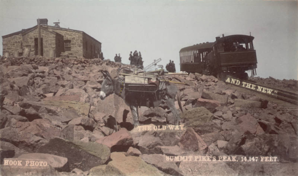 View of a Manitou and Pike's Peak Railway locomotive and passenger car at the summit of Pikes Peak in El Paso, County, Colorado. People wait in a boulder field outside the stone Army Signal Station; a pack burro is in the foreground.