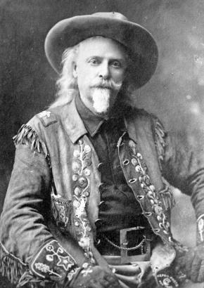 Photograph of a portrait, including frame, of head and shoulders of Buffalo Bill, seated, wearing decorated jacket and hat.