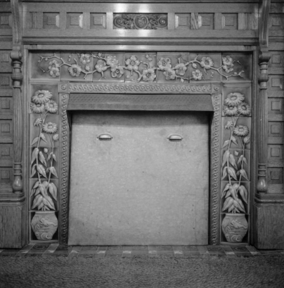 Interior view of the residence of T. B. Townsend, in Montrose, Colorado, shows an ornate fireplace surround with raised images of potted flowers along the sides and images of flowers on a branch across the top.