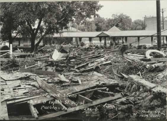 View of metal and wood debris, mud and silt from flooded Fountain Creek washed over Denver and Rio Grande Western Railroad tracks near the 8th (Eighth) Street depot in Pueblo (Pueblo County), Colorado.