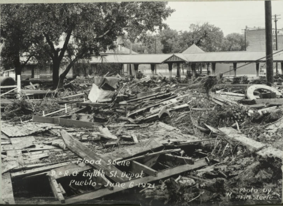View of metal and wood debris, mud and silt from flooded Fountain Creek washed over Denver and Rio Grande Western Railroad tracks near the 8th (Eighth) Street depot in Pueblo (Pueblo County), Colorado.