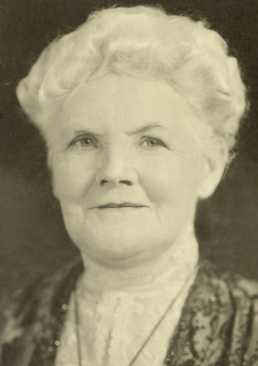 Studio bust portrait of Catherine Smith Mullen (Mrs. John Kernan Mullen) in a lace blouse and dress with a banded collar and a necklace. Mrs. Mullen has short, wavy hair.