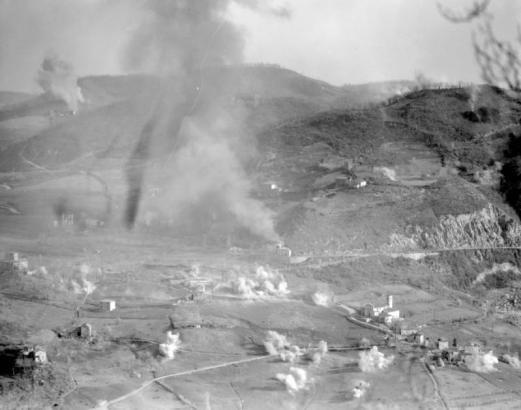 Following an aerial bombardment that opened the Tenth Mountain Division's offensive Saturday morning April 14, 1945, hundreds of guns poured high explosives on German-held houses and towns. Shows a concentration of artillery blasting the town of Roffeno Musiolo.