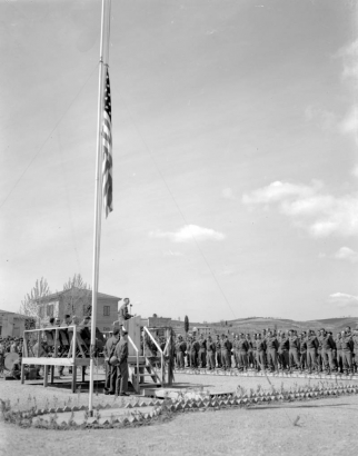 A view of the stage, flag pole, and the Tenth Mountain Division soldiers attending the Division's memorial held April 6, 1945, at the American Military cemetery in Castelfiorentino (Florence Province), Italy.