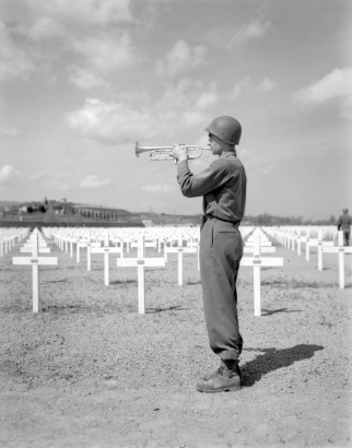 A bugler plays taps beside the rows of white crosses that mark the graves of servicemen who died in the Italian campaign during a memorial service held for the men of the Tenth Mountain Division on April 6, 1945, at the American Cemetery in Castelfiorentino (Florence Province), Italy.