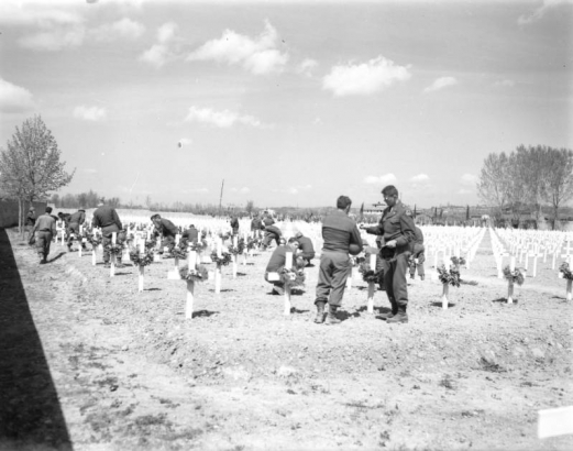 Shows group of Tenth Mountain Division soldiers decorating the graves of their comrads at the American Military cemetery in Castelfiorentino, Italy; probably after the memorial services held April 6, 1945.