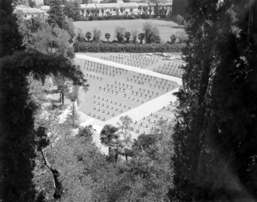 View taken from above of the American Military Cemetery, where many Tenth Mountain Division soldiers are buried, in Castelfiorentino, Italy. Shows rows of white crosses surrounded by trees.