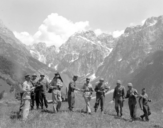 Rugged mountains form a backdrop for a group portrait including British Field Marshal Alexander, Tenth Mountain Division General George P. Hays, and unidentified Allied generals. The group had a luncheon in the tent in the background.