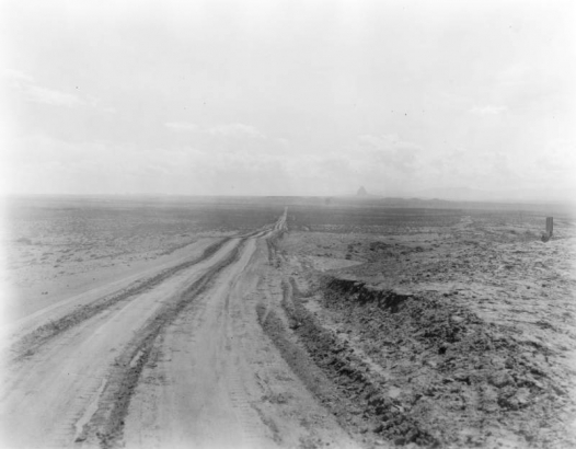 U.S. Highway 666 (now U.S. 491) recedes into the distance near the Colorado - New Mexico border; Ship Rock is on the horizon.