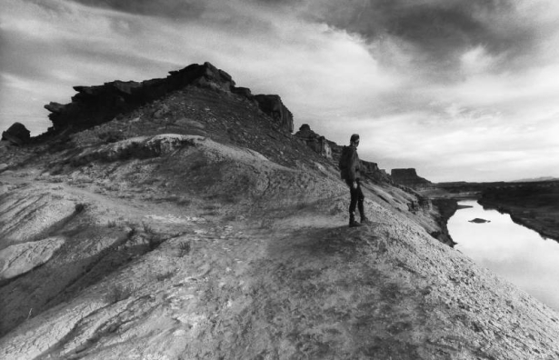 A cyclist stands looking at the Green River near Ft. Bottom on the White Rim Trail in Canyonlands National Park. The trail which runs through rough and rugged country for over one hundred miles is in the Island in the Sky District of Canyonlands. The p...