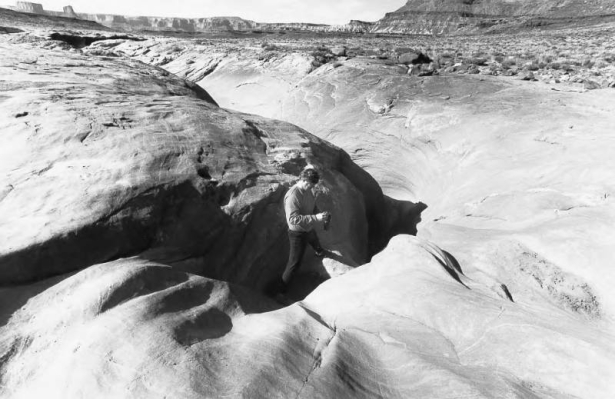 A cyclist traveling the White Rim Trail checks out The Black Crack. At many places along the trail a small crack opens up,becoming, eventually, a vast canyon. During its hundred mile length many canyons appear like this beside the trail. The White Rim ...