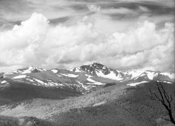 Patches of snow remain on Arapaho Peak during the summer in This distant view from the head of Gamble Gulch in Gilpin County, Colorado. Arapaho Peak is on the border of Boulder and Grand Counties. Cumulus and cirrus clouds fill the sky.