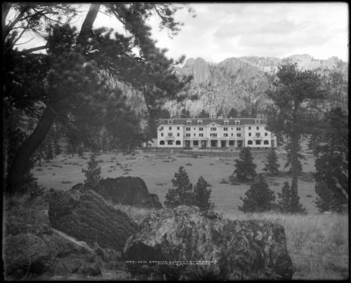 Exterior view of Stanley Hotel under construction, Estes Park, Colorado; hotel built by Freelan Oscar Stanley and completed in 1909; stone  masons or workmen building rock wall.