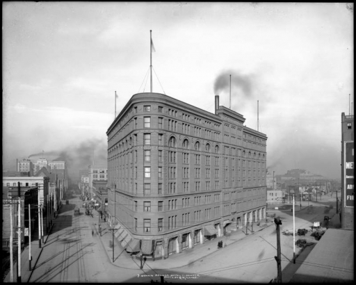 Exterior view of Brown Palace Hotel, Denver, Colorado; shows overview of hotel, streets, street car tracks, and wagons at the intersection of Broadway and 17th (Seventeenth) Street; backside of Equitable Building distant left and Denver High School, distant right.