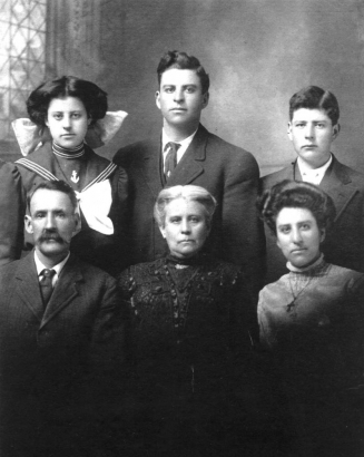 Group portrait of the Policarpio Córdova family from Trinidad (Las Animas County), Colorado. Front row left to right: Policarpio Córdova, Gumucinda Chacón, Isabel Córdova. Back row left to right: Rosa, Amadeo and Policarpio Córdova, Jr.  Rosa wears a sailor styled dress with white piping and an embroidered anchor. She has her hair parted in the middle and wears a large hair bow.