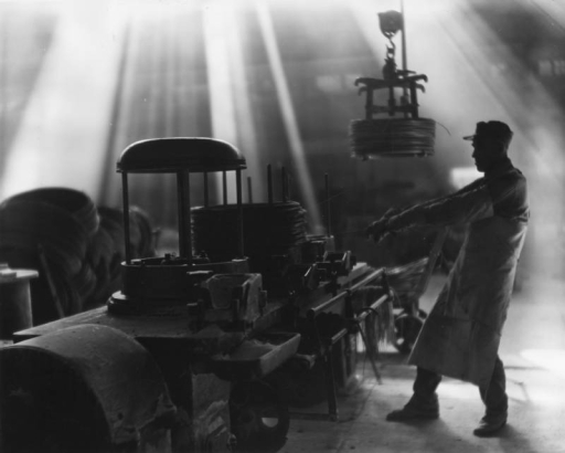 Interior view of Colorado Fuel and Iron Company (Corporation), Pueblo, Colorado, a steel and iron manufacturing plant; shows male employee  operating a machine which produces steel wire from steel rods.