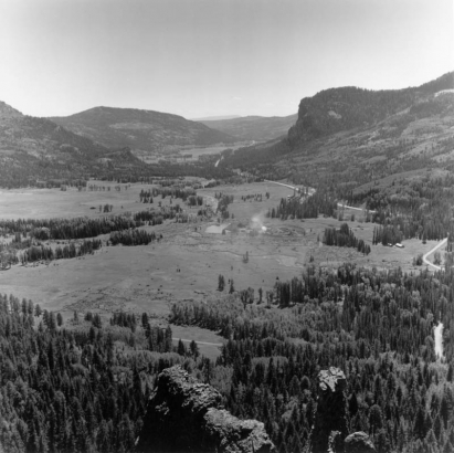 View of the upper San Juan Valley from Wolf Creek Pass in Mineral County, Colorado. Shows Highway 160, a gravel pit, a creek and rock formations.