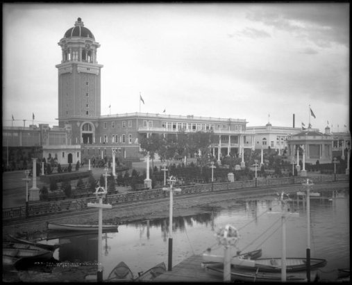 View across Lake Rhoda, the "White City" (later called Lakeside Amusement Park), Lakeside, Colorado, near Denver; shows bandstand or pavilion (gazebo), benches, Casino and tower, boats on shore, and miniature  railroad tracks around lake.