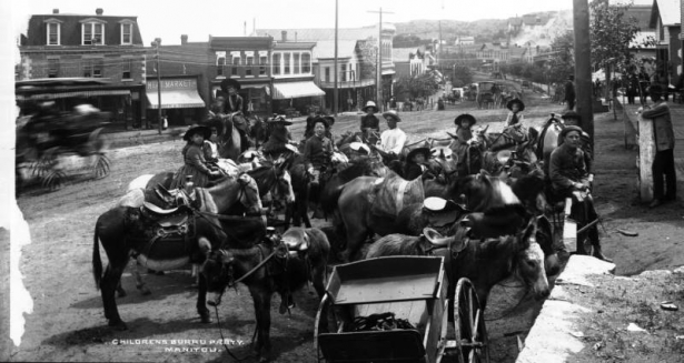 Children pose with burros on Manitou Avenue in Manitou Springs (El Paso County), Colorado. Business signs read: "Meat Market" and "Produce & Commission."