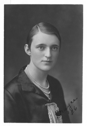 A studio portrait of Grayce Smith a possible student at North High School and a member of the Kismet Club.  She has her hair slicked back and is wearing a black stain top with white lace pinned to it.  She wearing a triple strand pearl necklace.