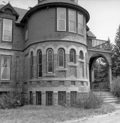 Tower detail of the Dos Rios Ranch Mansion built by Alonzo and Annie Hartman in 1892, west of Gunnison, Colorado. Fuller, a local Methodist minister designed the brick and wood sided house with Gothic and Victorian elements. A central tower has a series of stone arches with decreasing lengths of Italian stained glass windows.