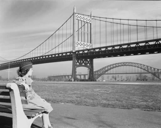 View of the Triborough Bridge and the Hell Gate Railroad Bridge in the borough of Queens, New York City, New York. A woman in uniform and garrison cap sits on a bench in Astoria Park.