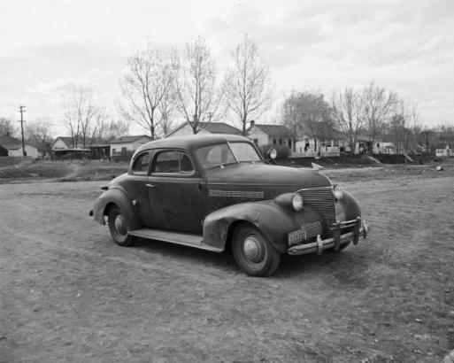 View of a 1939 Chevrolet Deluxe coupe automobile in (probably) Denver, Colorado.