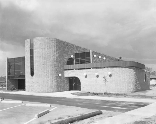 View of the modernist style Bear Valley Branch of the Denver Public Library (Anderson, Barker, and Rinker Architects) at 5171 West Dartmouth Avenue in the Harvey Park South neighborhood, Denver, Colorado. Features curved brick walls and arches, glass atriums, and spherical lamps.