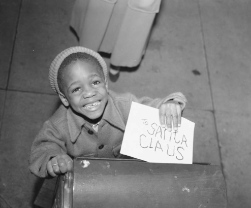 An African American (Black) boy mails a letter addressed to "Santa Claus" in (probably) Denver, Colorado.