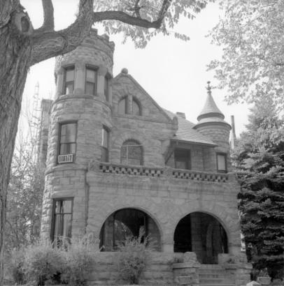 Exterior view of "Gargoyle" House, 302 West Pitkin Avenue, Pueblo, Colorado, shows a two-story rock-faced stone residence with corner tower, turret, balustrade, and semi-elliptical double-arched porch.