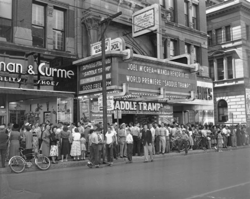 People crowd the 16th (Sixteenth) Street entrance of the Tabor Theater in Denver, Colorado. The marquee reads: "Joel McCrea and Wanda Hendrix on the Stage, World Premiere of Saddle Tramp."