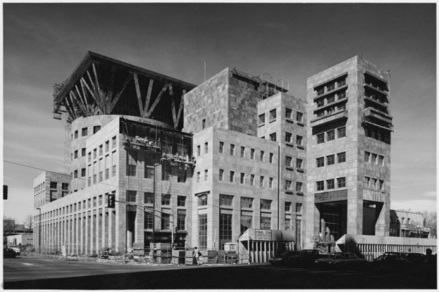 View of the Denver Public Library at 1357 Broadway Street (at 13th Avenue) in the Civic Center Neighborhood of Denver, Colorado. Construction workers on scaffolds work on the stone cladding of the Michael Graves addition; pedestrian shelter reads: "Hyman Etkin Construction."