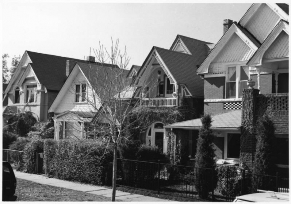 View of homes in the Baker Neighborhood of Denver, Colorado; features include shingle imbrication, covered porches, bargeboard, arched windows, corbeled brick, and an inset balcony.