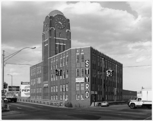 View of the (former) McPhee-McGinnity building at Broadway and (2560) Walnut Street in the Five Points neighborhood of Denver, Colorado. The four-story brick building has a domed clock tower, ceramic trim, and a sign: "STYRO."