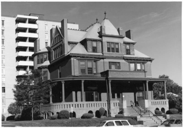 View of the Charles Taylor House (Architects Kirchner & Kirchner, built 1891) at 1311 York Street in the Cheesman Park Neighborhood of Denver, Colorado. The three-story brick and sandstone mansion has a covered wraparound porch, bay windows, a turret, chimneys and ridgecresting. Mid-rise apartments are to the side.