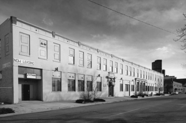 View of a brick commercial building at the corner of 25th (twenty fifth) and Curtis Street, in the Curtis Park Neighborhood of Denver, Colorado; features include a portico, parapet, dark brick coursing and corbels Stone lintel reads: "Ideal;" entry awning reads: "Eric's Pub."