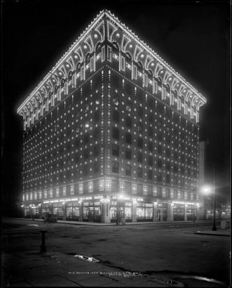 Exterior night view of illuminated Gas & Electric building (later Insurance Exchange building), 15th (Fifteenth) and Champa, Denver, Colorado; opened November 10, 1910 displaying over 10,000 exterior light bulbs decorating building; illuminated advertising above doorways and window displays: "Gas ranges, water heaters, electric washing machines, utility motors, toasters, all our gas ranges guaranteed....gas water heaters at reduced prices."