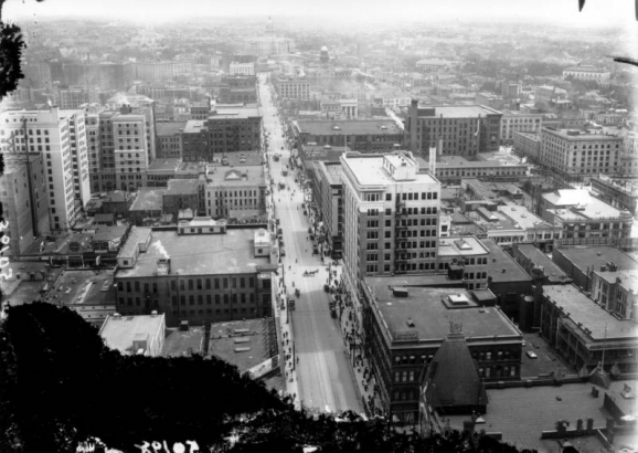 Southeast overlook view above Sixteenth (16th) Street, Denver, Colorado. Landmarks include the Arapahoe County Courthouse, the Cathedral of the Immaculate Conception, and the Colorado State Capitol Building. Signs read: "The May Co.," "Joslin's Dry Goods," "M. Philipsborn & Co., Cloaks and Suits," and "Kodaks."